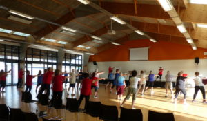 Photo of a group of people doing tai chi in a big sunny hall.