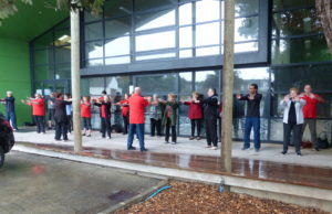 Group of people doing tai chi under a small verandah and trying not to get wet