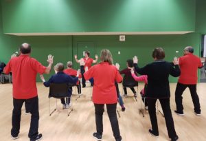 Group of people doing tai chi. Some seated