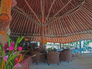 Comfy cane chairs and tables in an open-sided tropical, thatched-roof building