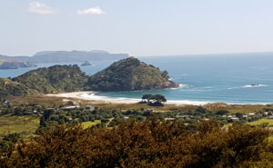 Green bushy hills, white sand beach and azure blue sea