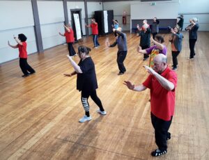 Group of people in a hall doing tai chi poses