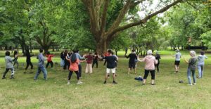 Group of people doing tai chi outdoors under a big tree