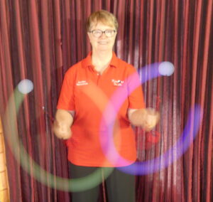 Woman in red shirt twirling poi (balls on a string)