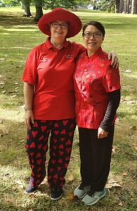 Two women in red. One wearing trousers with hears and the other in a traditional Cheongsam (Chinese dress)