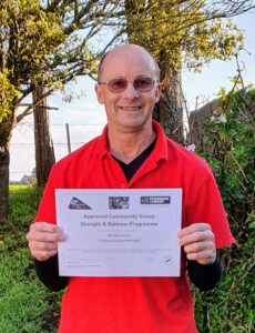 Smiling man in red shirt holding a certificate