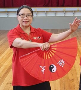 Smiling woman in red shirt with a red fan