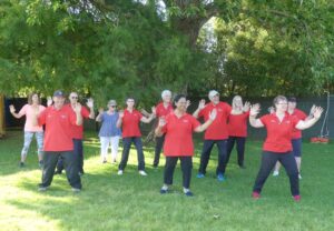 Group of people smiling while doing tai chi in a park