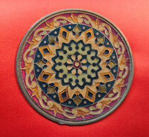Geometric design of diamond shapes, circles, and swirls in light green, gold, navy blue and burgundy red