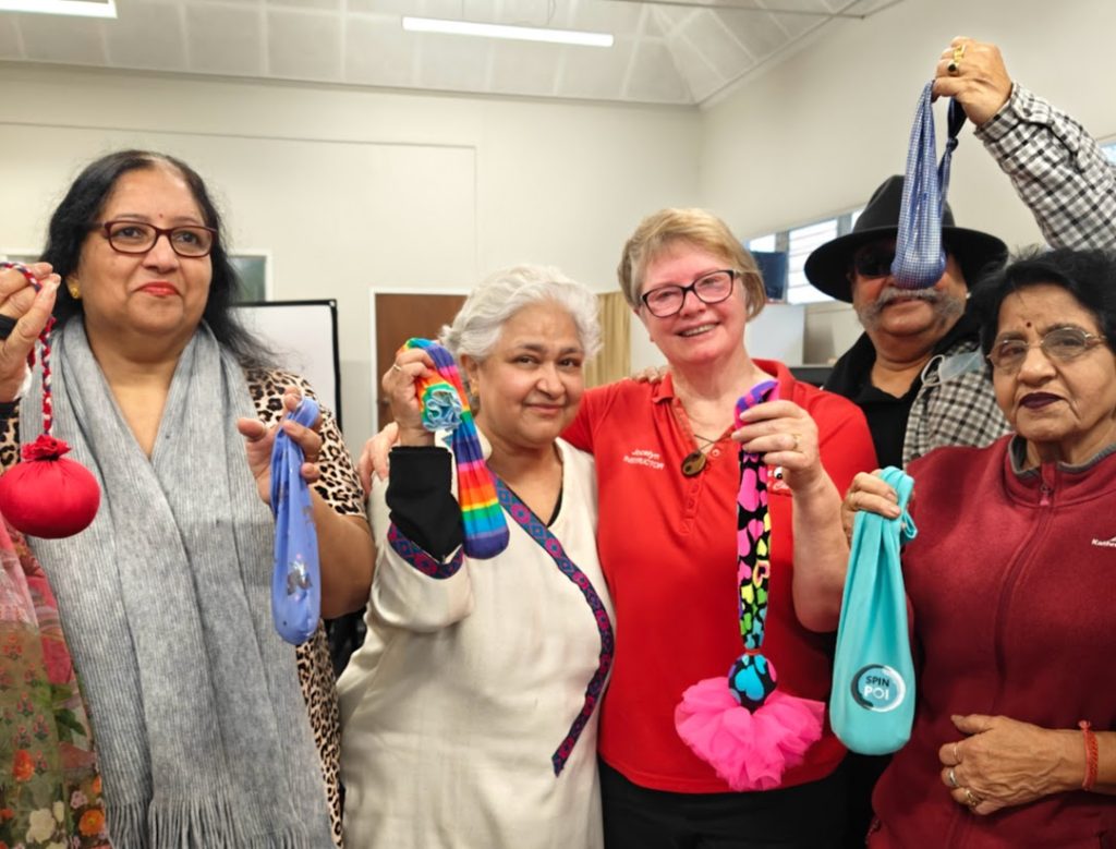 Group of five people smiling, all holding poi